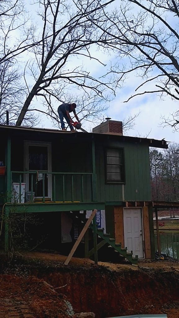 Man cutting roof sheathing with a chainsaw
